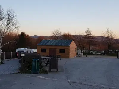 a building with a picnic table in a parking lot at Wyreside Lakes Glamping Pods in Lancaster