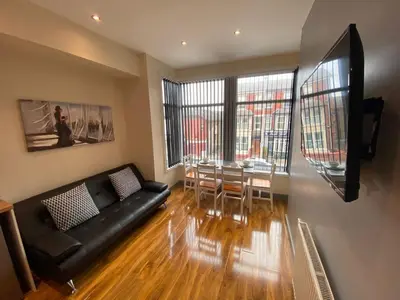 a living room with a black couch and a table at Seaside Suites Superior Family Apartments in Blackpool