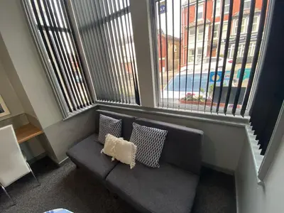 a couch in a room with two large windows at Seaside Suites Superior Family Apartments in Blackpool