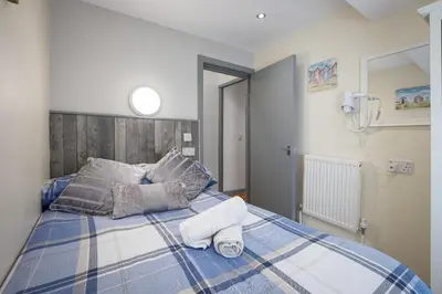 a blue and white bed with two towels on it at Seaside Suites Superior Family Apartments in Blackpool