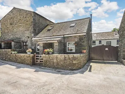 a stone building with a gate and a fence at Thimble Cottage in Ulverston
