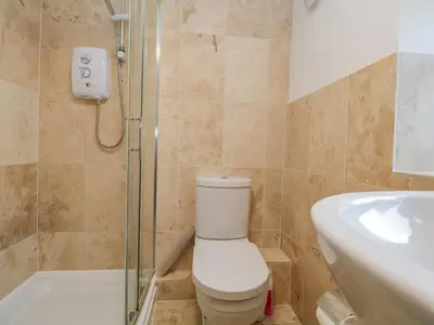 a bathroom with a toilet and a shower and a sink at Thimble Cottage in Ulverston