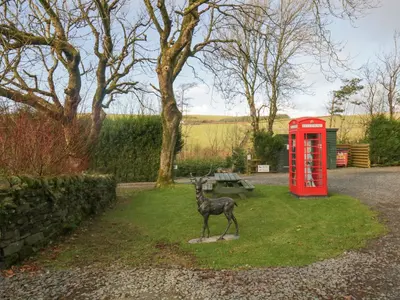 a statue of a deer next to a red phone booth at Thimble Cottage in Ulverston
