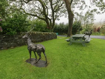 a statue of a deer standing in the grass next to a picnic table at Thimble Cottage in Ulverston