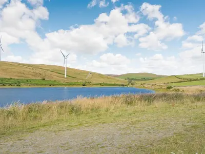 two wind turbines on a hill next to a lake at Thimble Cottage in Ulverston