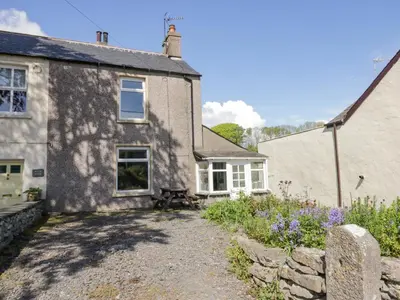 an old stone house with a garden in front of it at Beech Cottage in Ulverston