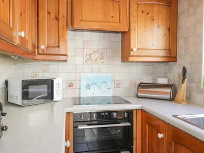a kitchen with wooden cabinets and a microwave at Beech Cottage in Ulverston