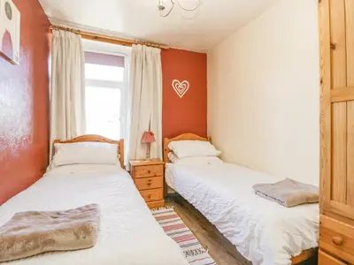 two beds in a room with red walls and a window at Beech Cottage in Ulverston
