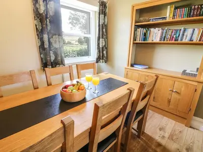 a dining room table with a bowl of fruit and two glasses of orange juice at Riverside View in Grange Over Sands