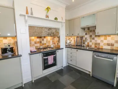a large kitchen with white cabinets and appliances at Riverside View in Grange Over Sands