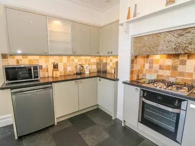 a kitchen with white cabinets and a stove top oven at Riverside View in Grange Over Sands