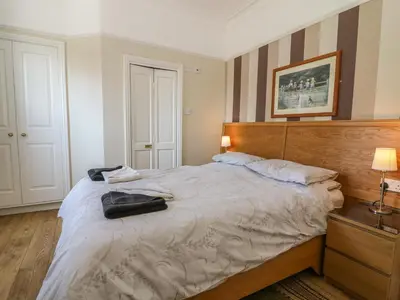 a bedroom with a large bed with a wooden headboard at Riverside View in Grange Over Sands