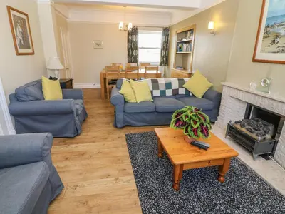 a living room with blue couches and a fireplace at Riverside View in Grange Over Sands