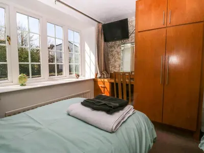 a bedroom with a bed with a dresser and windows at The Old Mill in Grange Over Sands