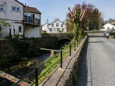 a fence on the side of a road with houses at The Old Mill in Grange Over Sands