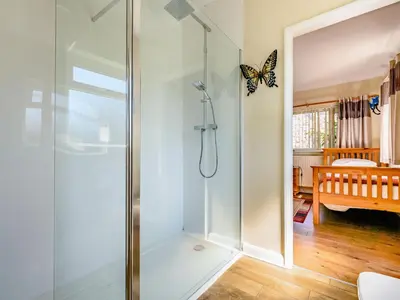 a glass shower stall in a bathroom with a butterfly on the wall at Eden House in Ulverston