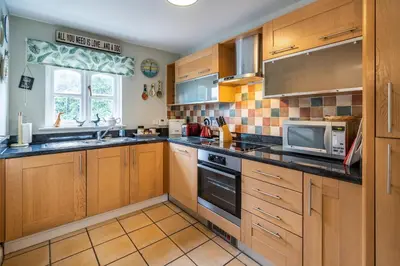 a kitchen with wooden cabinets and a sink and a microwave at Amber Cottage in Holker