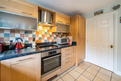 a kitchen with wooden cabinets and a stove top oven at Amber Cottage in Holker