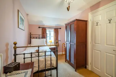 a bedroom with a bed and a wooden cabinet at Amber Cottage in Holker