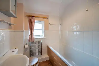 a bathroom with a tub and a toilet and a sink at Amber Cottage in Holker
