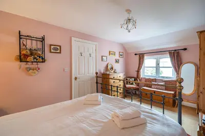 a bedroom with a large bed and a mirror at Amber Cottage in Holker
