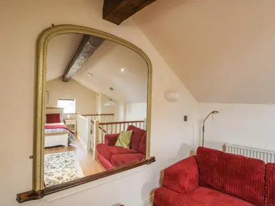 a large mirror in a living room with a red couch at Beck Cottage in Ulverston