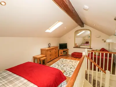 a bedroom with a red bed and a mirror at Beck Cottage in Ulverston