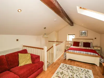 a bedroom with a bed and a red couch at Beck Cottage in Ulverston