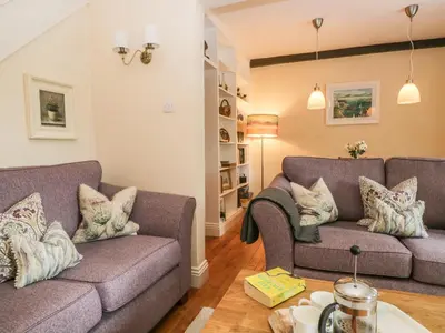 a living room with two couches and a table at Mulberry Cottage in Grange Over Sands