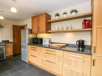 a kitchen with wooden cabinets and a stainless steel refrigerator at Mulberry Cottage in Grange Over Sands