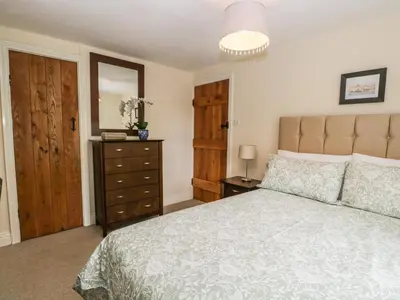 a bedroom with a bed and a dresser and a mirror at Mulberry Cottage in Grange Over Sands