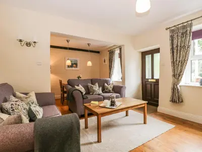 a living room with a couch and a table at Mulberry Cottage in Grange Over Sands