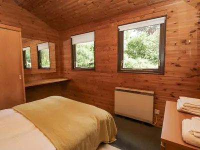 a bedroom with wooden walls and a bed and windows at Grasmere in Ulverston