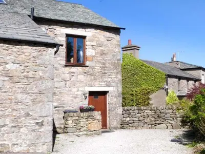 a stone building with a door and a window at The Byre in Grange Over Sands
