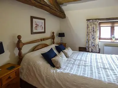 a bedroom with a large bed with blue pillows at The Byre in Grange Over Sands