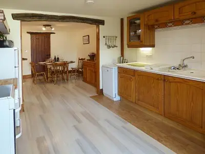 a kitchen with wooden cabinets and a table in it at The Byre in Grange Over Sands