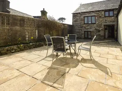 a patio with chairs and a table in front of a building at The Byre in Grange Over Sands