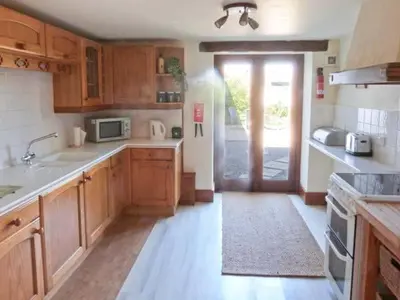 a kitchen with wooden cabinets and a door to a yard at The Byre in Grange Over Sands