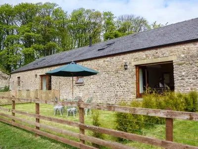 a brick building with an umbrella next to a fence at Poppy Cottage in Lancaster