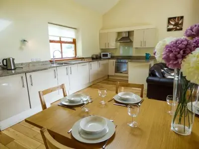 a kitchen with a wooden table with plates and wine glasses at Poppy Cottage in Lancaster