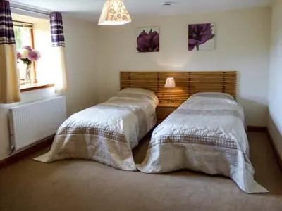 a bedroom with two beds with white blankets at Poppy Cottage in Lancaster