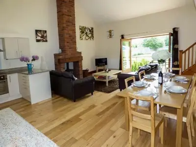 a living room with a table and a couch and a kitchen at Poppy Cottage in Lancaster