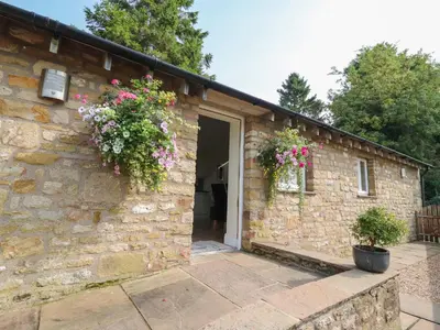 a stone house with flowers on the side of it at Stable Cottage in Burton in Lonsdale