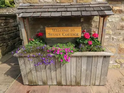 a flower box with a welcome to strate coffee sign at Stable Cottage in Burton in Lonsdale