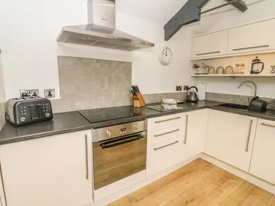 a kitchen with white cabinets and a sink at The Potting Shed in Carnforth