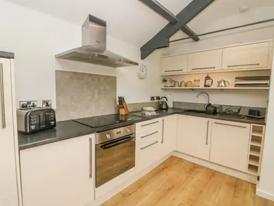a kitchen with white cabinets and black counter tops at The Potting Shed in Carnforth