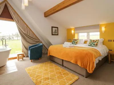 a bedroom with a bed and a tub and a sink at Bluebell Cottage in Ulverston