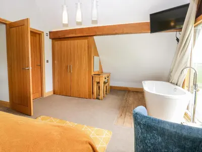 a bathroom with a tub and a tv in a room at Bluebell Cottage in Ulverston