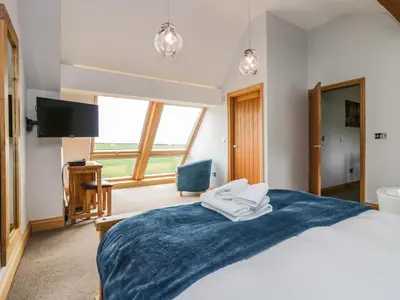 a bedroom with a large bed with a blue blanket at Bluebell Cottage in Ulverston