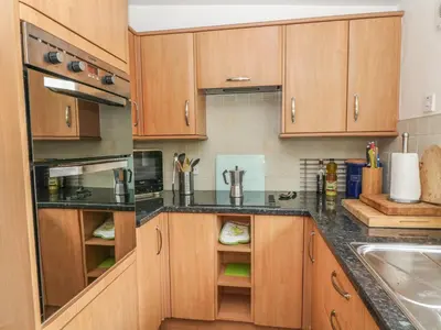 a kitchen with wooden cabinets and black counter tops at Rosemary Cottage in Carnforth